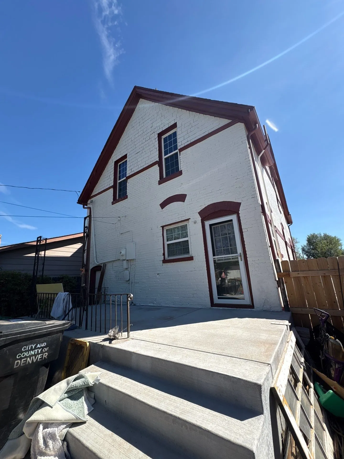 Rear of a historic Denver Victorian after repainting, white painted brick with Carriage Door red window trim and brick arches