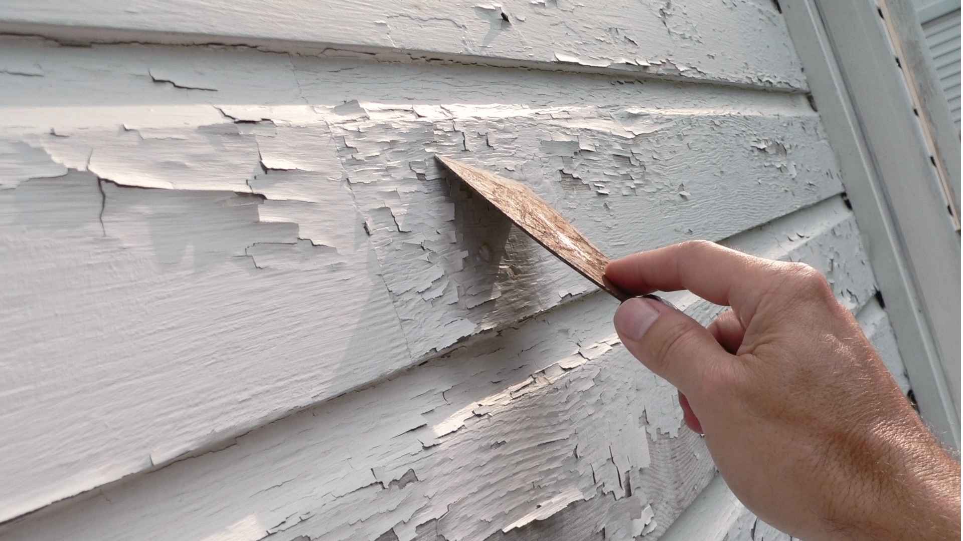 Photo of a painter scraping failing paint